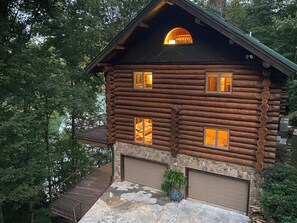 Standalone cabin with a central entrance, flanked by windows, set amidst lush greenery.