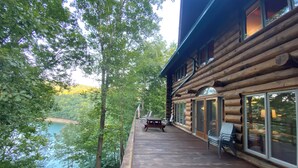 A wooden cabin with a deck overlooking a lake, featuring large windows and a flag. - The Cabin on Fontana Lake
Lake Front Paradise in the Smokies (Robbinsville)