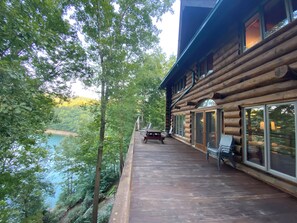 Relax on the deck overlooking the serene water, surrounded by lush greenery and taking in the views through large windows.