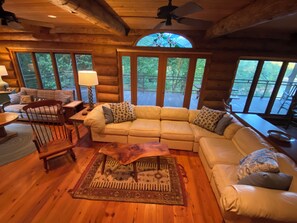 Relax in this cabin's spacious living area, featuring a plush sofa, wooden coffee table, and a rug with intricate designs.