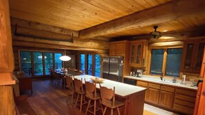 A spacious kitchen with wooden cabinets, a large island with bar stools, a refrigerator, and a dishwasher. - The Cabin on Fontana Lake
Lake Front Paradise in the Smokies (Robbinsville)
