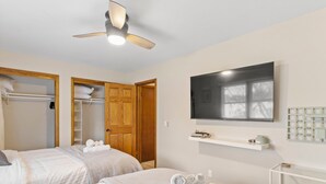 A hotel room with two beds, a ceiling fan, a TV, and a wardrobe. - Spacious 3-BD Townhouse W/PKG 25M From Airport (Milwaukee)