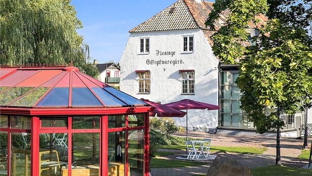Un bâtiment traditionnel de couleur blanche, sur lequel on peut lire l’inscription « Fleninge Gæfifmaregård ».