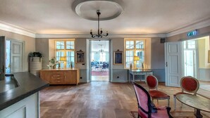 Une salle à manger spacieuse avec une longue table, plusieurs chaises et un lustre.