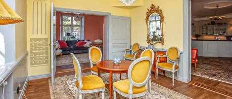A dining area with a round table, yellow chairs, and a chandelier.