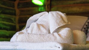 A stack of white towels on a bed in a room with a green-lit wall. - Chalé Saíra - Eco.hospedagem. Sinta a Natureza Imerso em paz e Tranquilidade (Praia Grande)
