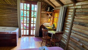 A log cabin room with a wooden bed, a desk, and a bathroom. - Chalé Saíra - Eco.hospedagem. Sinta a Natureza Imerso em paz e Tranquilidade (Praia Grande)
