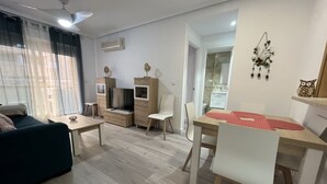 A modern living room with a sofa, a TV stand, a dining table with chairs, and a ceiling fan. - ACV - Costa Azahar I-2ª linea planta 3 norte (OROPESA)