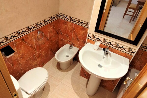 Un baño pequeño con inodoro, bidé y lavamanos.