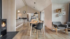 A spacious dining area with a wooden table and chairs, a kitchen with a stove, and a living area with a sofa and a TV.