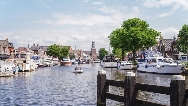 A canal with boats docked, a wooden pier, and buildings with traditional architecture. - 2 bedroom beautiful home in Lemmer (Lemmer)