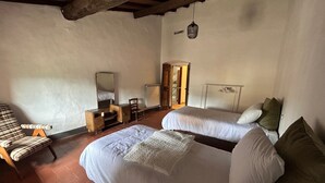 A room with two beds, a chair, a desk, and a wardrobe. - Casa Osci: Simple and Cozy Apartment with Vineyard Views in the Heart of Chianti (Panzano In Chianti)