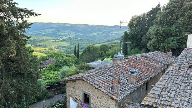 A stone building with a tiled roof, a small entrance, and a view of a valley. - Casa Osci: Simple and Cozy Apartment with Vineyard Views in the Heart of Chianti (Panzano In Chianti)