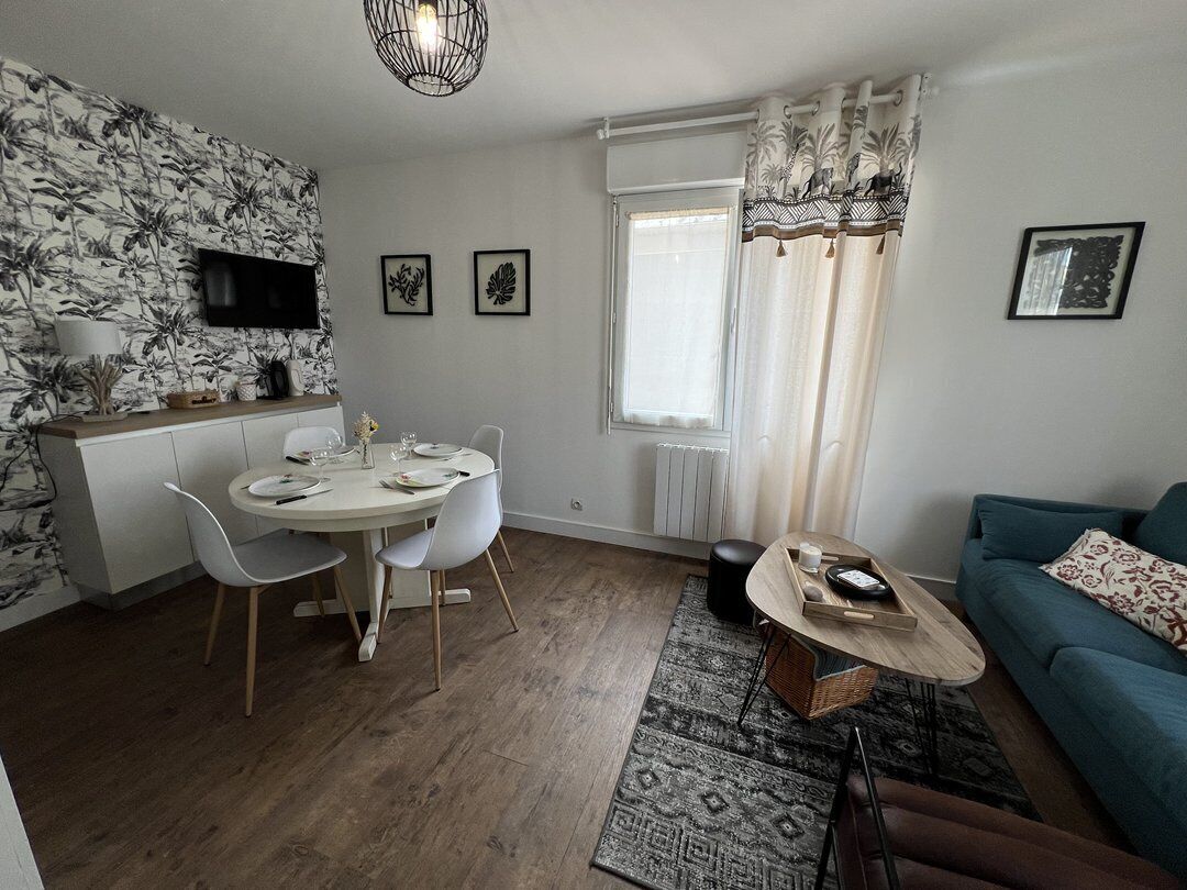 A modern living room with a dining area, a sofa, a TV, and a window with curtains.