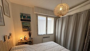 Ein Schlafzimmer mit einem großen Bett, einer Nachttischlampe, einem Fenster mit Vorhängen und einem Wandbild.