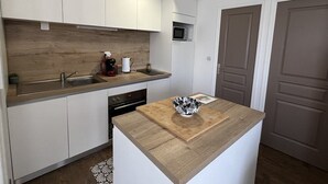 Eine moderne Küche mit weißen Schränken, einer Holzauskładung, einer Mikrowelle, einem Spülbecken und einem Geschirrgestell.
