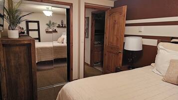Een hotelkamer met een groot bed, een houten kledingkast, een spiegel en een nachtkastje met een lamp.