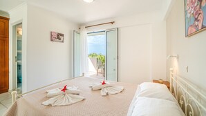 A hotel room with a bed, a door, a window, and a view of the outside. - Apartment 'Premier Studio Downstairs 9' with Sea View, Wi-Fi and Air Conditioning (arillas kerkyra)