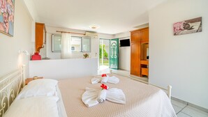 A hotel room with a bed, a bathroom, a TV, and a view of the outside. - Apartment 'Premier Studio Downstairs 9' with Sea View, Wi-Fi and Air Conditioning (arillas kerkyra)