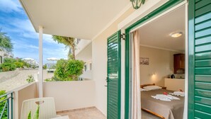 Een balkon met een bloempot, een stoel en een bed met handdoeken.