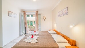 Een hotelkamer met twee bedden, een schuifdeur naar een balkon en uitzicht op een gebouw.