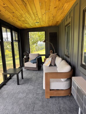 A modern interior with a wooden ceiling, large windows, a sofa, a small table, and a radiator.