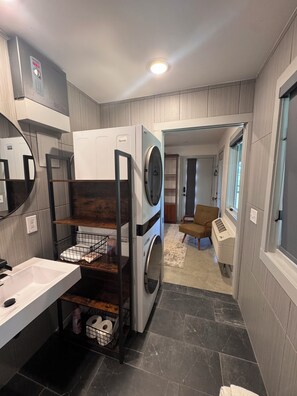 A compact laundry room with a washing machine, dryer, and a small sink.