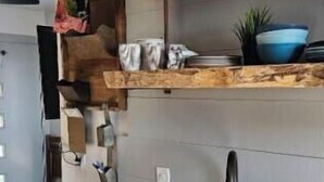 Eine moderne Küche mit doppelter Spüle, Holzregalen und einer hängenden Pflanze.