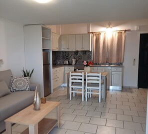 A compact living space with a kitchenette, a dining area, and a sofa. - Studio Apartment 'Premier  Upstairs 6' with Sea View, Wi-Fi and Air Conditioning (arillas kerkyra)