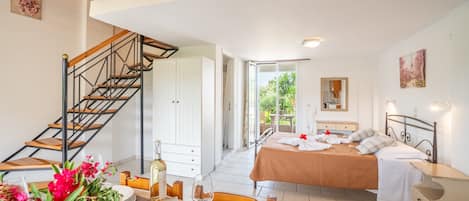 A bedroom with a bed, bedside tables, a nightstand, a window, and a staircase.