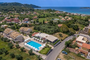 Vista aérea de una zona residencial costera con piscina, casas y una carretera.
