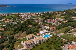 An aerial view of a coastal town with a swimming pool, residential buildings, and a church.