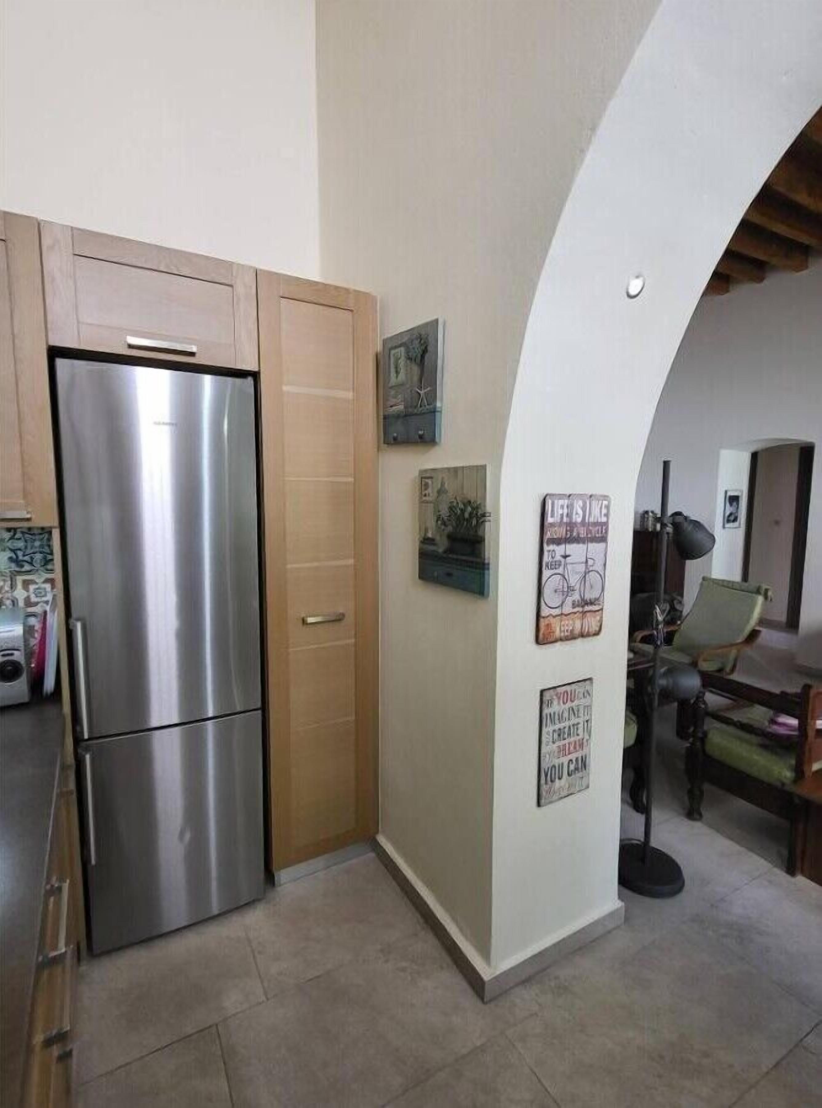 A kitchen with a stainless steel refrigerator, wooden cabinets, and a wall with motivational posters.