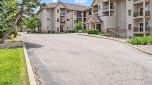 Un immeuble résidentiel à plusieurs étages doté d’une entrée centrale, de balcons et d’un parking.