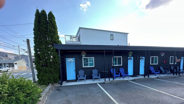 A motel with numbered doors, outdoor seating, and a parking lot. - Old Orchard Beach Motel (Old Orchard Beach)