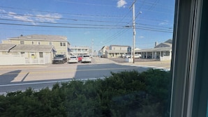 A view through a window with a mesh screen, displaying a street scene with buildings, cars, and power lines. - Old Orchard Beach Motel (Old Orchard Beach)