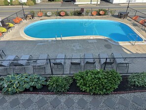 A swimming pool with a fenced deck area, surrounded by chairs and tables. - Old Orchard Beach Motel (Old Orchard Beach)