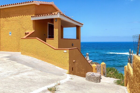 A coastal building with a balcony, a clear view of the sea, and a parking sign.
