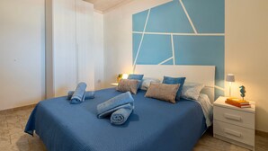 A bedroom with a bed, pillows, a nightstand, a lamp, and a wall art piece.