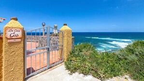 A coastal property named 'La Casa di Gio' with a metal gate and a view of the ocean.