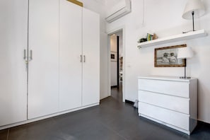 Un couloir avec une armoire blanche, une commode blanche et un tableau encadré accroché au mur.