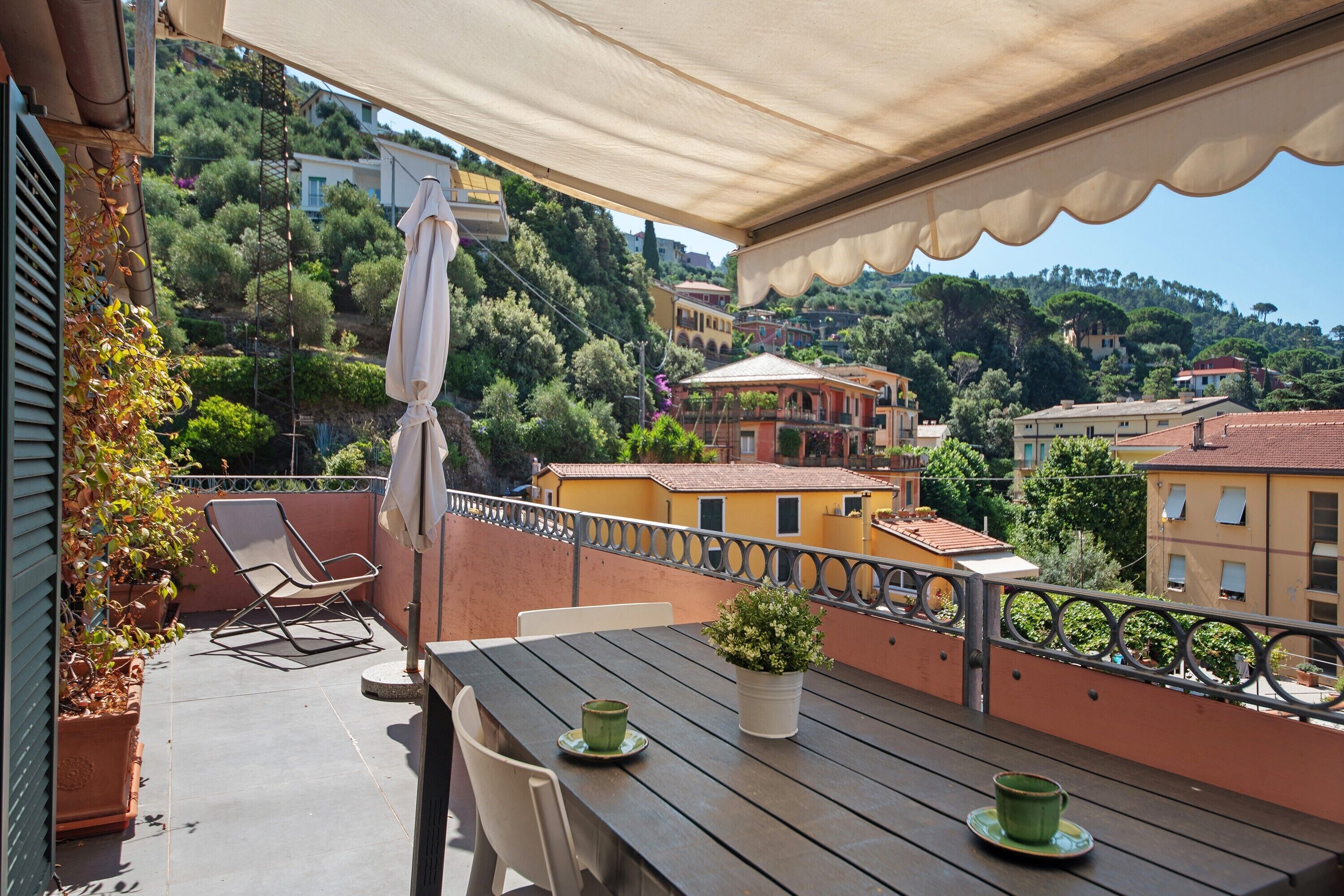 Eine Terrasse mit Tisch, Stühlen und einem Blumentopf.
