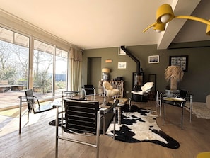 A modern living room with a large window, a black and white cowhide rug, and a yellow pendant light.