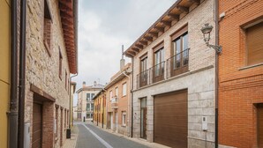 Una calle estrecha flanqueada por edificios con fachadas de ladrillo, grandes portones de garaje y un camino adoquinado.