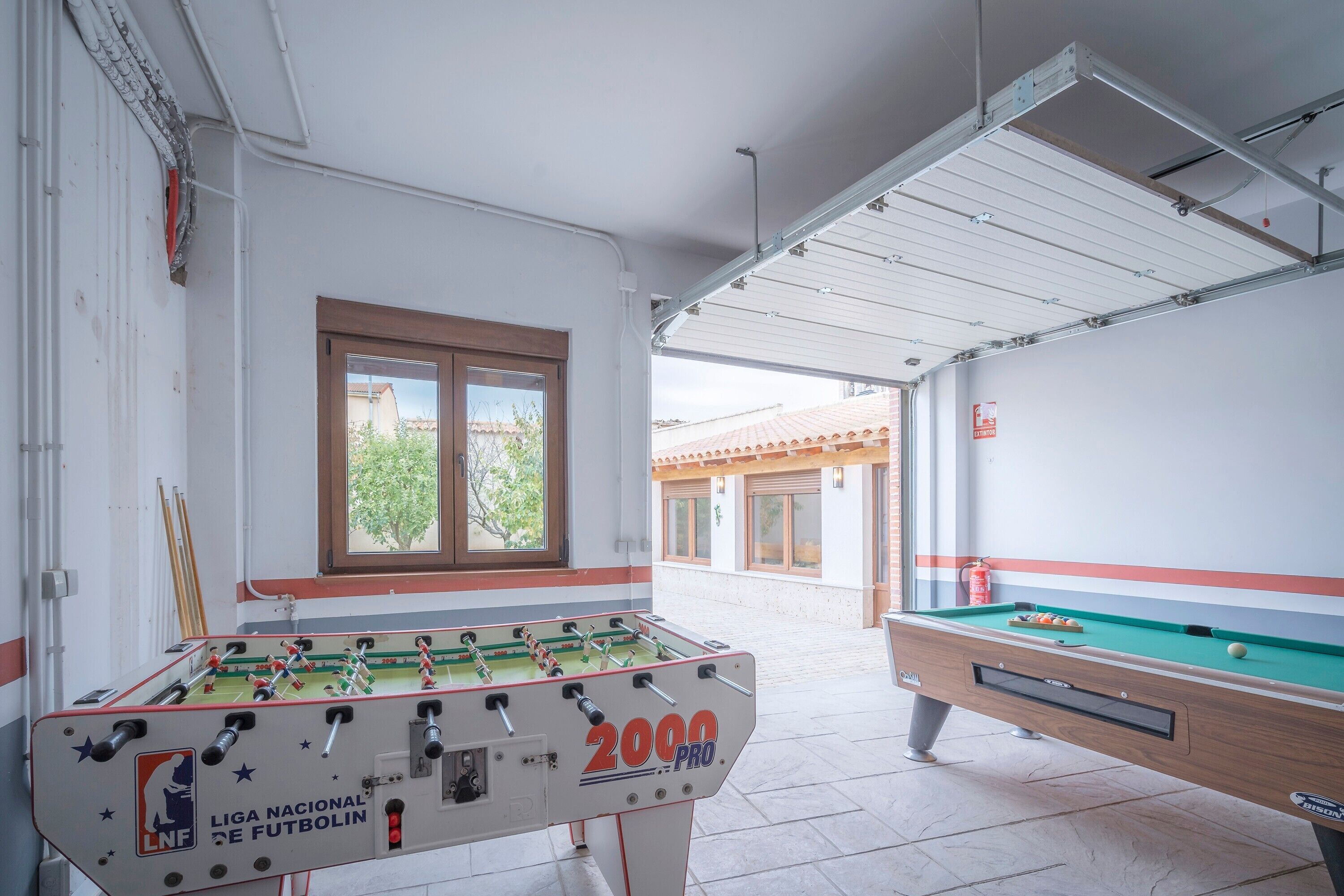 Une table de baby-foot, une table de billard et une fenêtre donnant sur des immeubles.