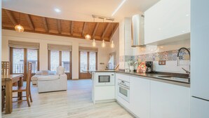 Una cocina moderna con armarios blancos, horno empotrado y microondas.