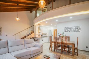 Un salon moderne comprenant un canapé, une table à manger et des chaises, un escalier et un coin cuisine.