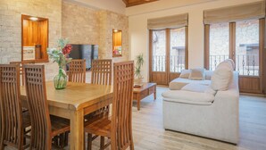 Amplia sala de estar con una mesa de comedor de madera, sillas, un sofá y un televisor.