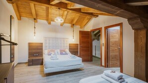 Un dormitorio con techo de madera, una cama con almohadas, una mesita de noche y un armario de madera.