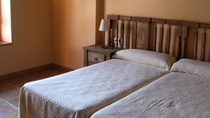 Une chambre avec deux lits, une table de chevet, une lampe et un élément décoratif fixé au mur.
